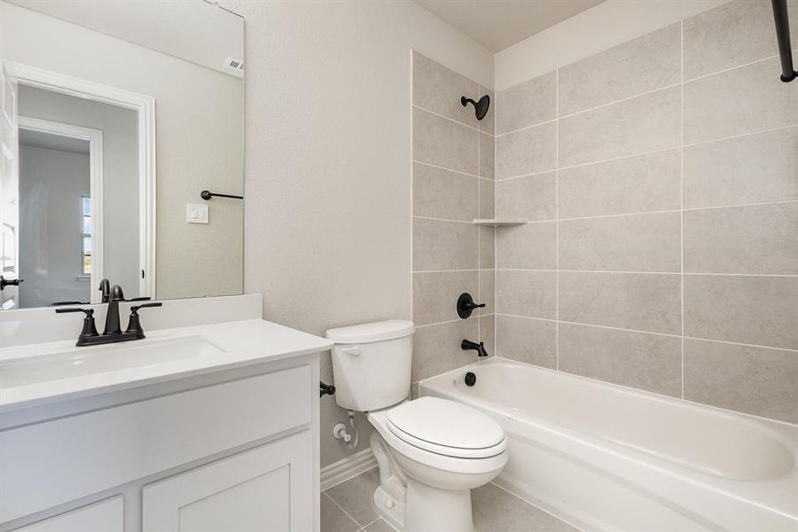 Full bathroom with tiled shower / bath, vanity, toilet, and tile patterned floors