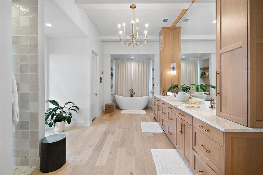 Bathroom featuring hardwood / wood-style floors, vanity, a washtub, and a notable chandelier