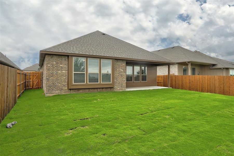 Rear view of property with a lawn and a patio