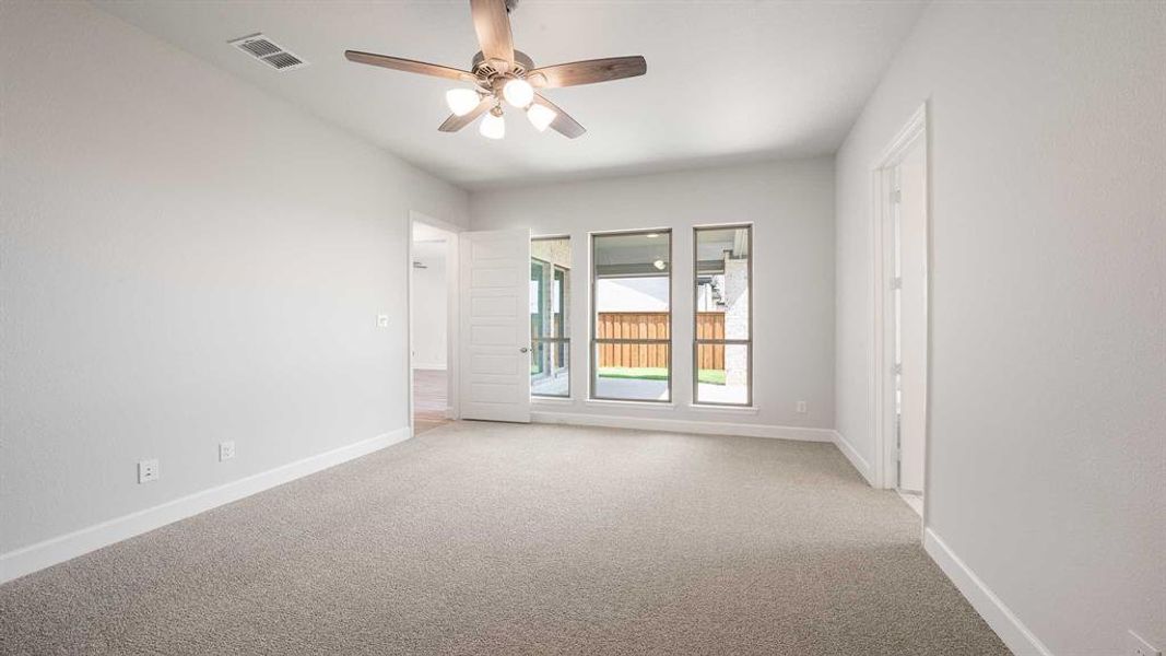 Empty room with light colored carpet and ceiling fan