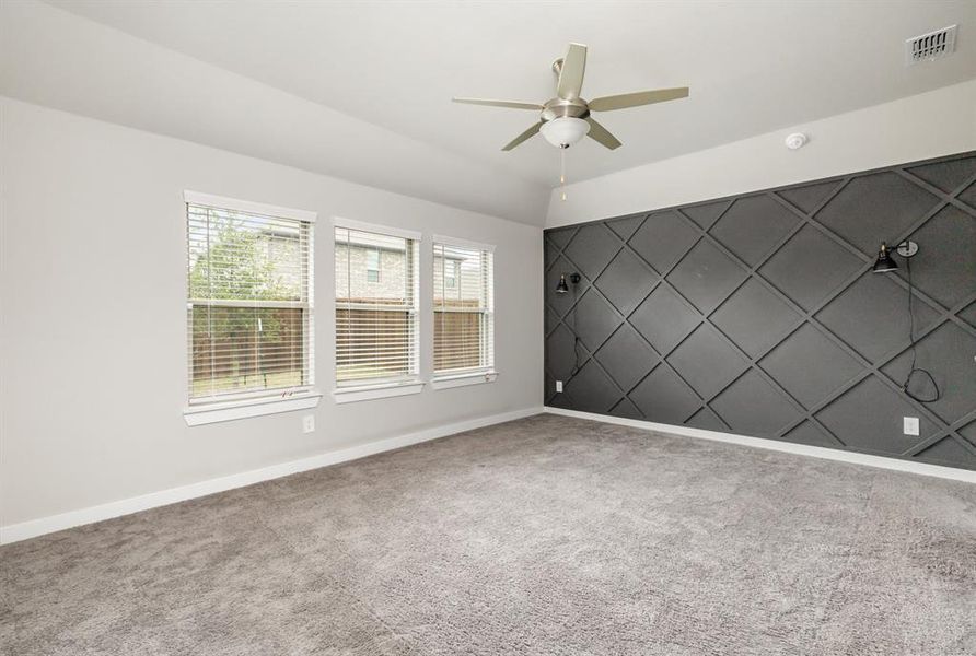 Spare room featuring a wealth of natural light, ceiling fan, and carpet flooring
