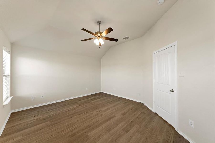 Empty room featuring lofted ceiling, dark hardwood / wood-style flooring, and ceiling fan