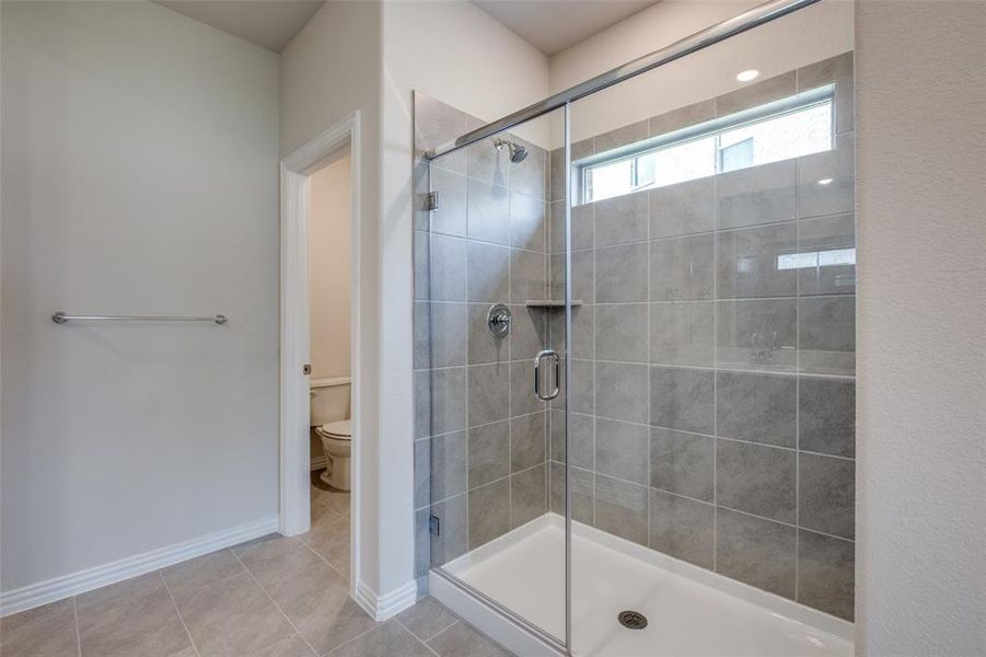 Bathroom with walk in shower, tile patterned floors, and toilet