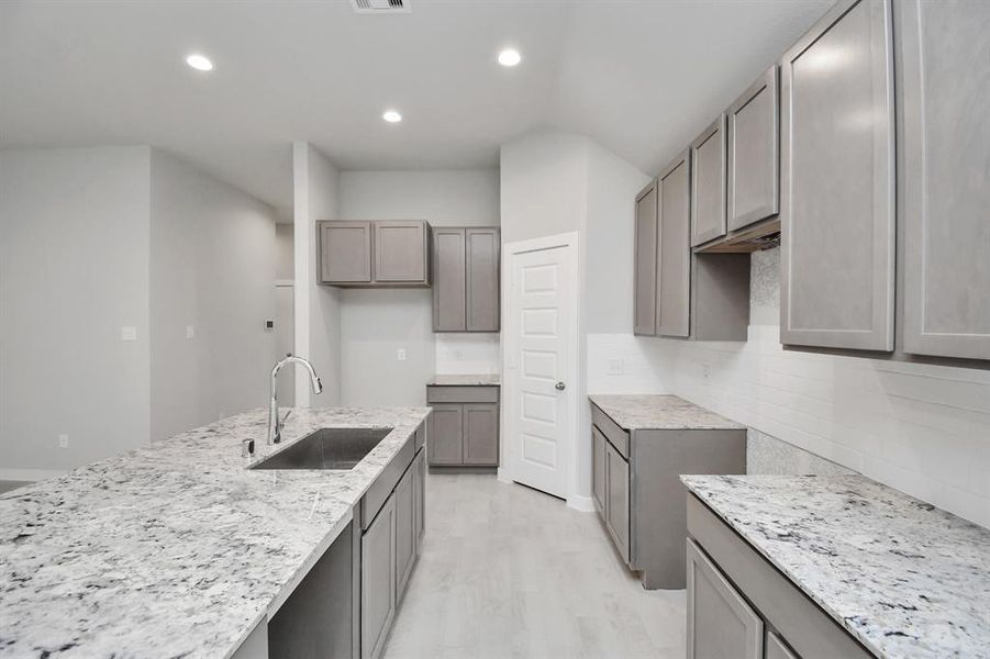 Discover another perspective of this stunning kitchen, generously appointed with an abundance of counter space. Sample photo of completed home with similar plan. Actual color and selections may vary.