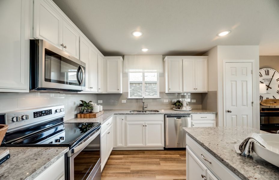 Spacious kitchen with large window, recessed lighting, and built-in appliances