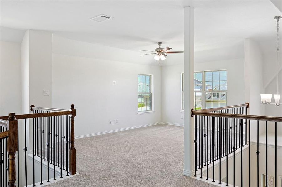 Empty room with ceiling fan with notable chandelier and light colored carpet