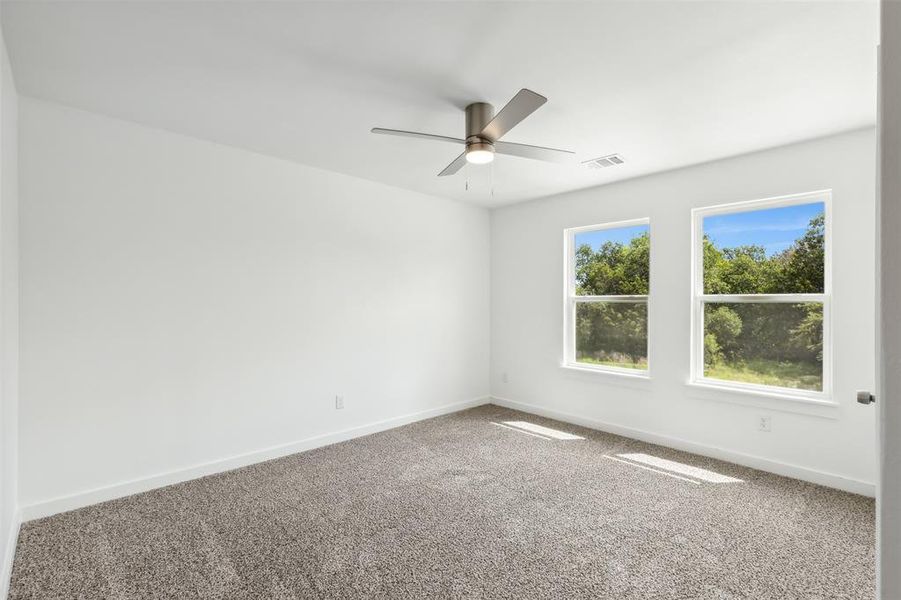 Spare room featuring carpet and ceiling fan
