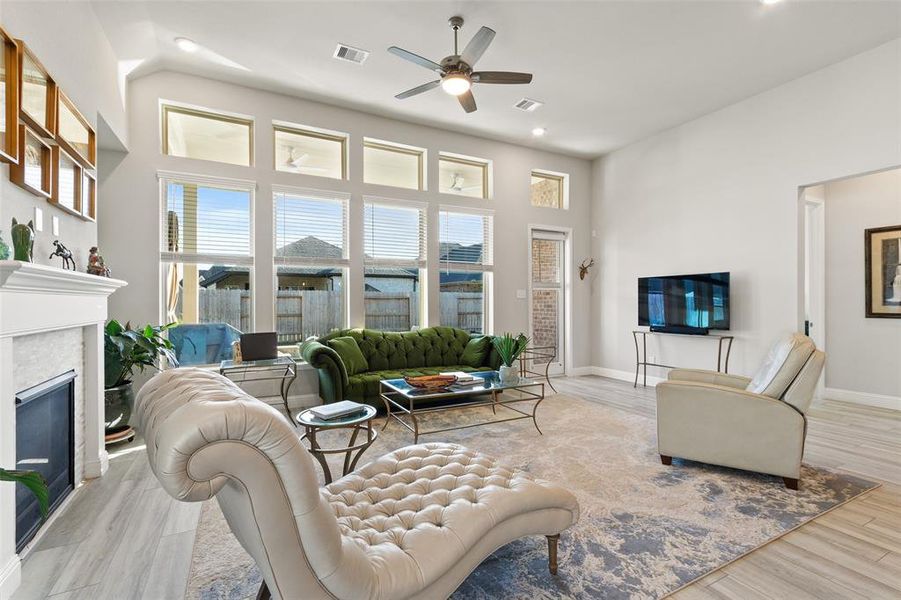 Cozy family room featuring a warm fireplace and expansive windows offering stunning views of the lush backyard and inviting pool.