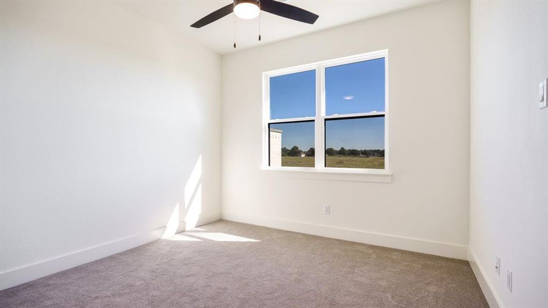 Empty room featuring light colored carpet and ceiling fan