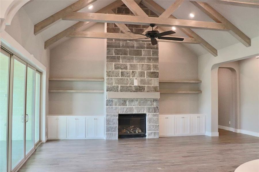 Unfurnished living room featuring high vaulted ceiling, ceiling fan, light wood-type flooring, and a fireplace