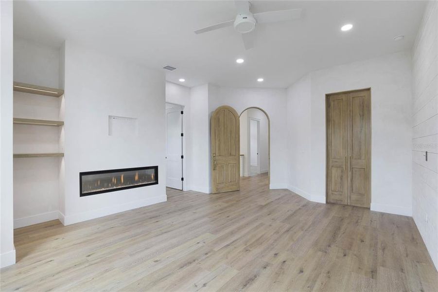 Owners suite arched entry door. Lit floating shelves and fireplace.