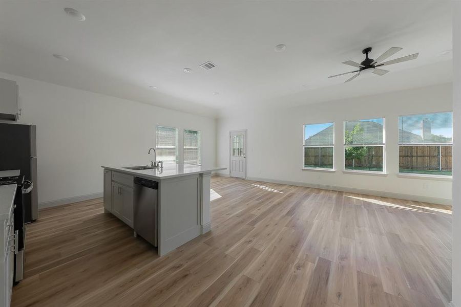 Kitchen featuring a center island with sink, light wood-type flooring, sink, and a healthy amount of sunlight