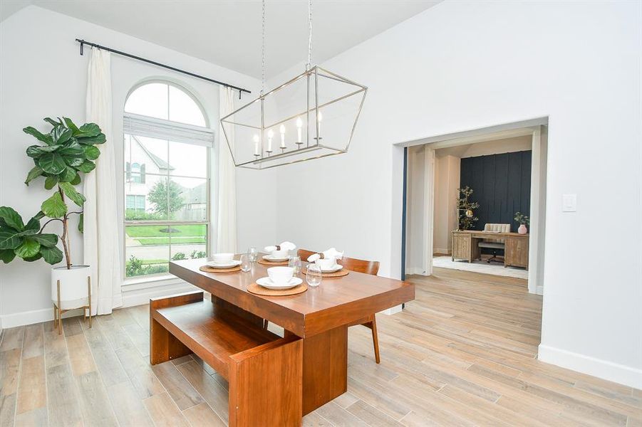 A bright dining area with high ceilings, large arched window, and a modern light fixture.