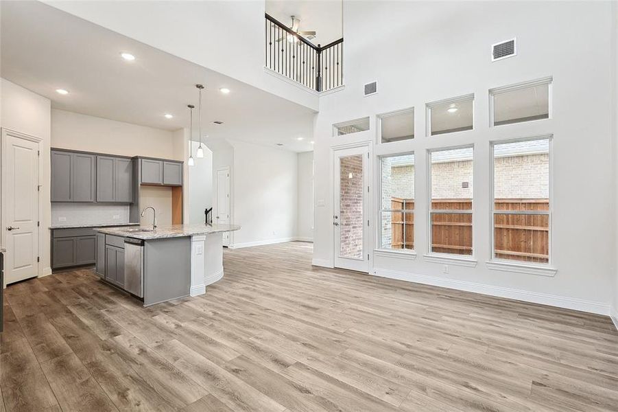 Kitchen featuring a center island with sink, a high ceiling, gray cabinetry, and light wood-type flooring