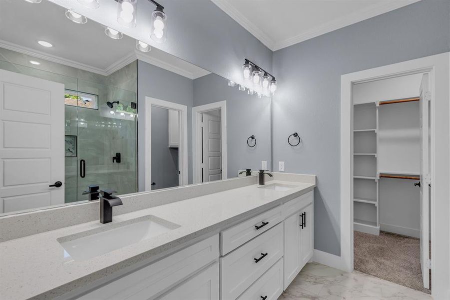 Bathroom featuring ornamental molding, tile floors, a shower with door, oversized vanity, and dual sinks