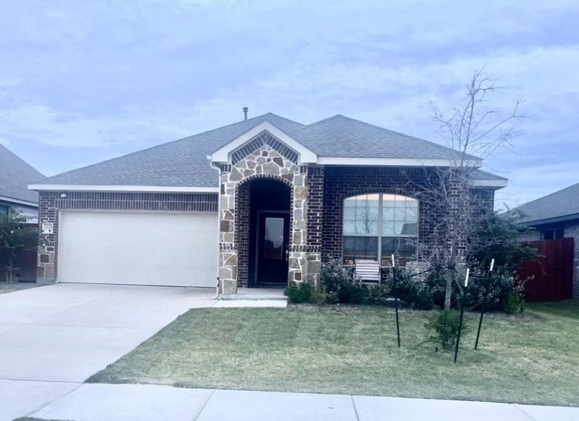 View of front facade featuring a front lawn and a garage