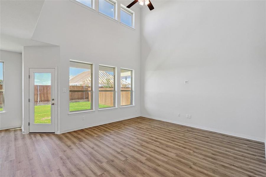 Unfurnished room with ceiling fan, a high ceiling, hardwood / wood-style floors, and plenty of natural light