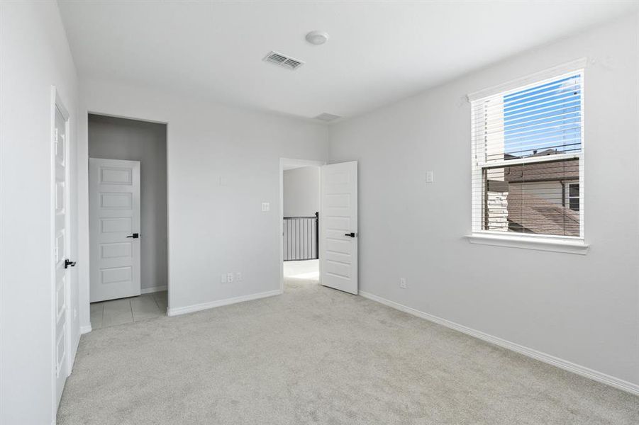 The third bedroom upstairs features plush carpet and a large window.