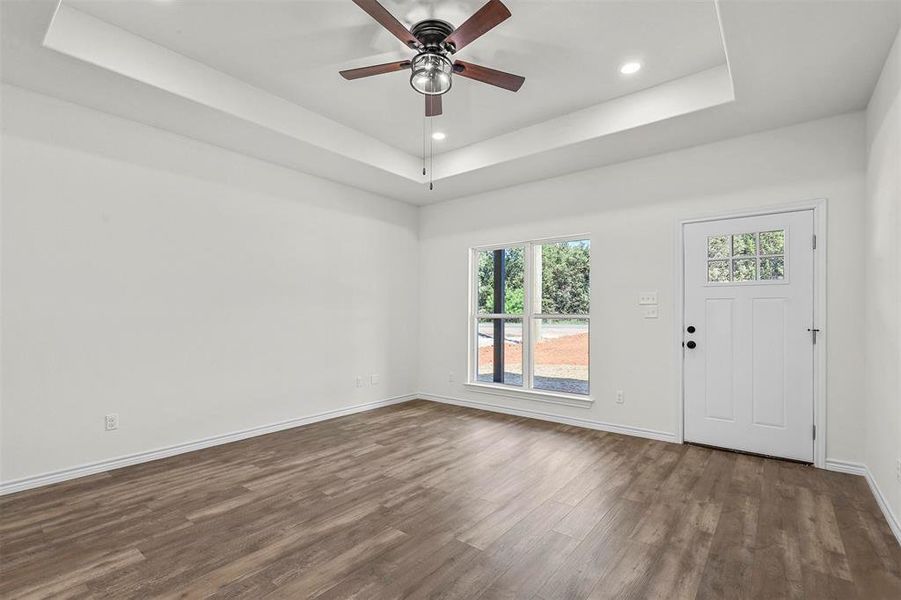 Entrance foyer featuring a wealth of natural light, dark wood-type flooring, ceiling fan, and a tray ceiling