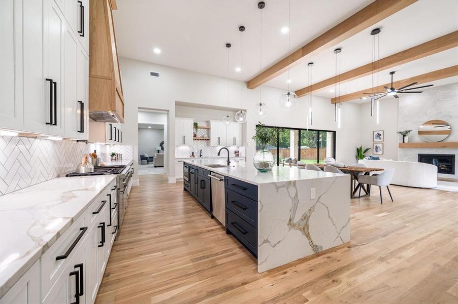 Kitchen with white cabinetry, stainless steel appliances, decorative backsplash, hanging light fixtures, and light hardwood / wood-style floors