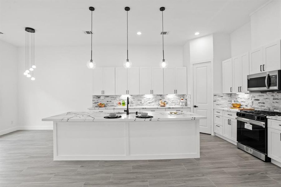 This beautiful upgraded gourmet kitchen features pendant lighting and beautiful island.