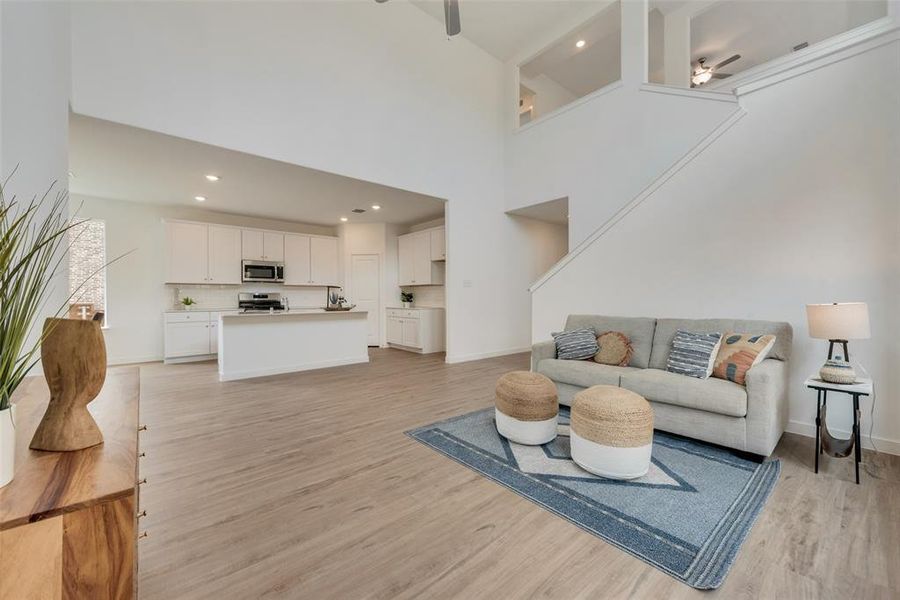 Living room featuring light wood-type flooring, a high ceiling, and ceiling fan