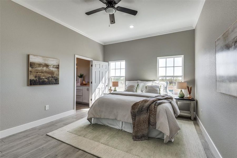 Primary Bedroom with crown molding, light wood-type flooring, ceiling fan, and ensuite bathroom