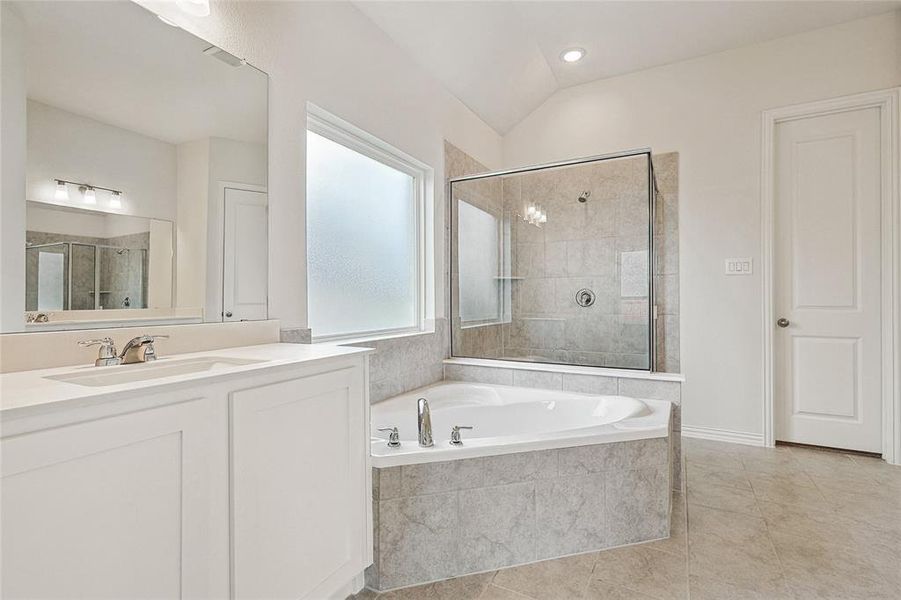 Bathroom featuring shower with separate bathtub, lofted ceiling, vanity, and tile patterned floors