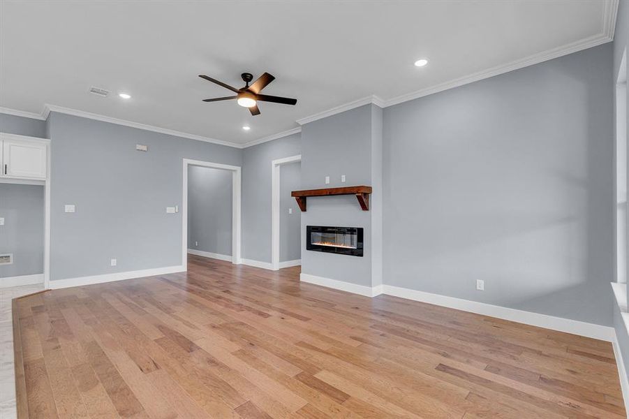 Unfurnished living room with ceiling fan, light hardwood / wood-style flooring, and crown molding