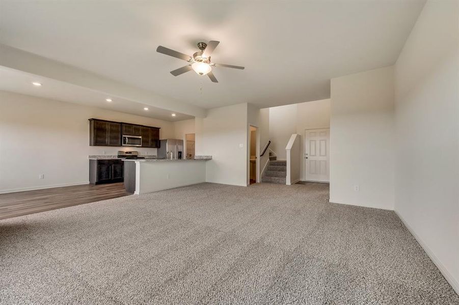 Unfurnished living room featuring ceiling fan and carpet floors