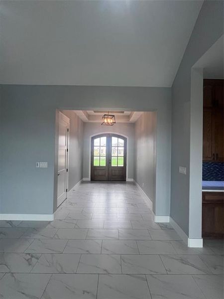 Entryway with an inviting chandelier, french doors, and vaulted ceiling