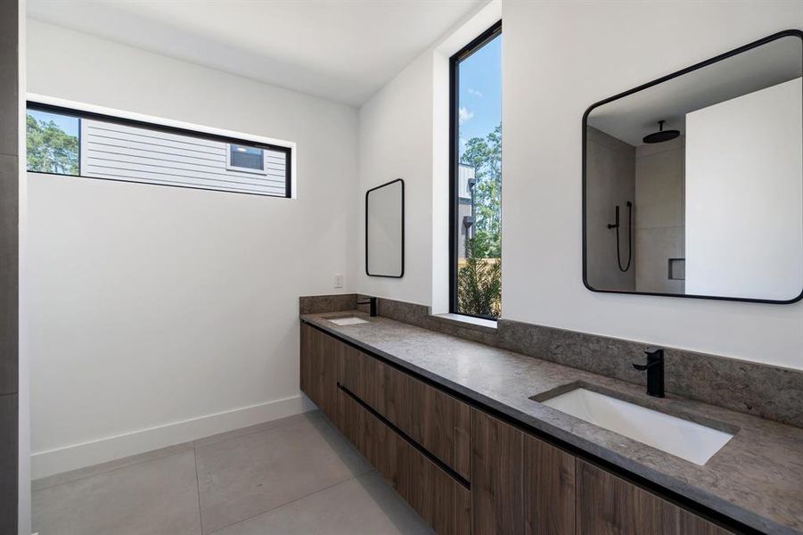 This is a modern bathroom featuring sleek dark fixtures, a large mirror, and a floating vanity with ample counter space. It has a neutral color palette and is well-lit by natural light from a tall window and a horizontal slit window.