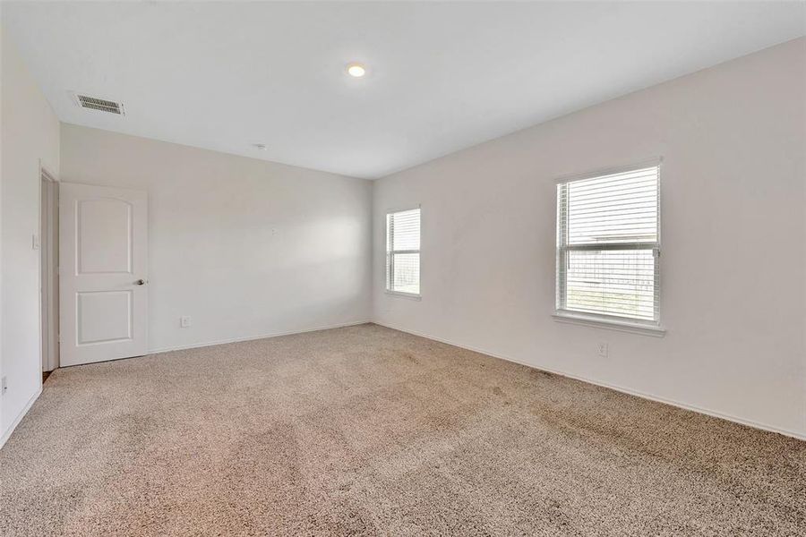 Another view of the primary bedroom. Two nice sized windows flood the room with natural light.