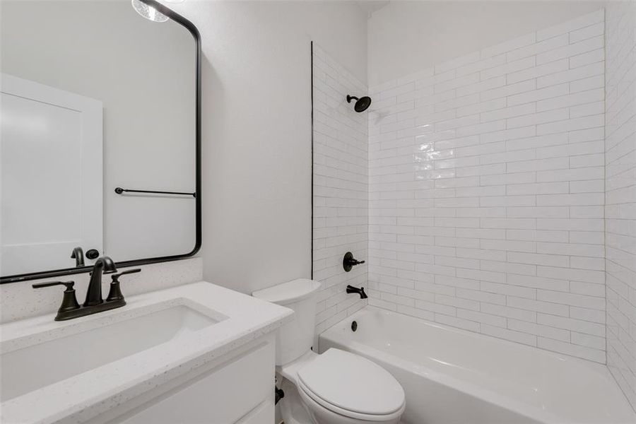 Full bathroom with vanity, tiled shower / bath, and toilet