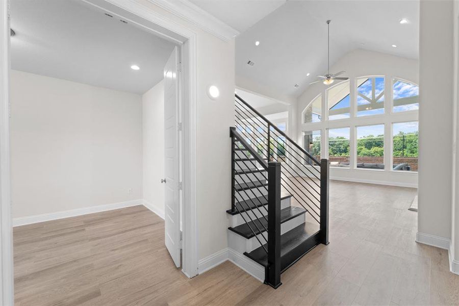 Staircase featuring ceiling fan, vaulted ceiling, and wood-type flooring