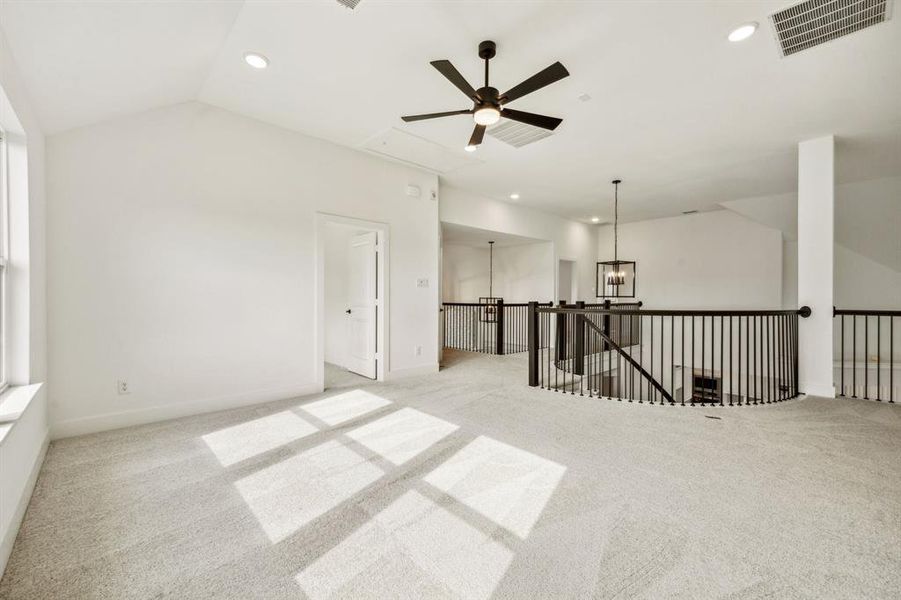 Unfurnished room with lofted ceiling, ceiling fan with notable chandelier, and light carpet