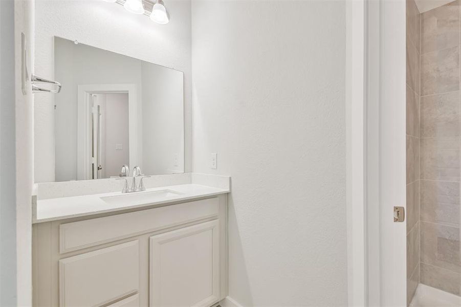 This is a clean and modern bathroom featuring a large vanity with a wide mirror and a single sink. Neutral color tones and bright lighting create an inviting space.