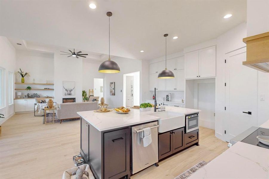 Kitchen with stainless steel appliances, white cabinetry, pendant lighting, light stone countertops, and light hardwood / wood-style flooring