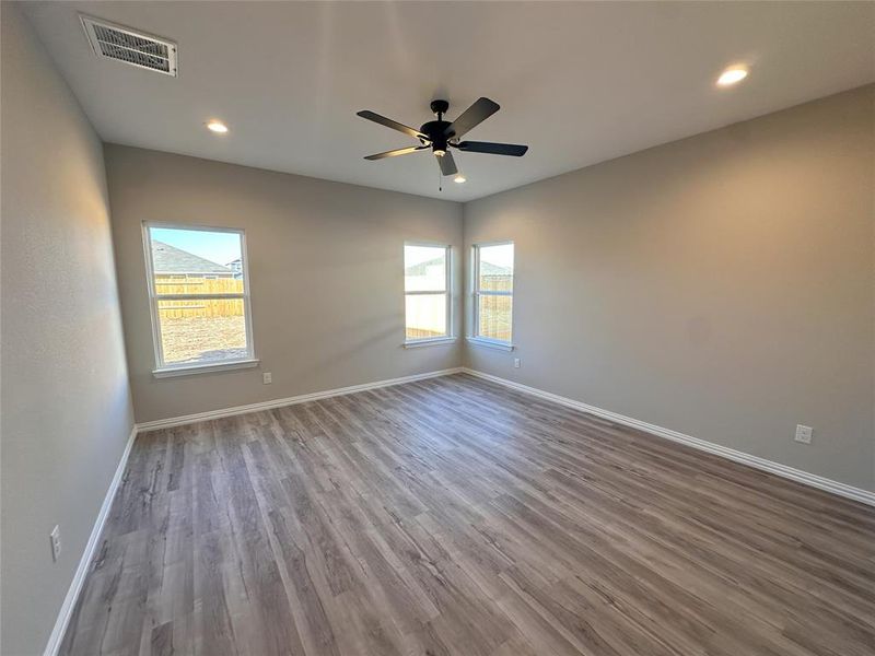 Spare room featuring a healthy amount of sunlight, hardwood / wood-style floors, and ceiling fan