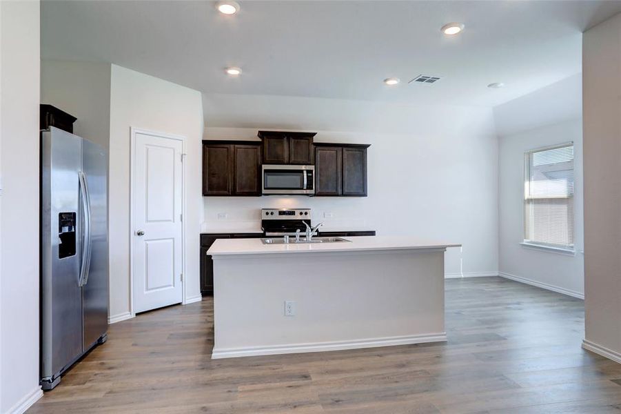 Kitchen featuring appliances with stainless steel finishes, a center island with sink, and light hardwood / wood-style flooring