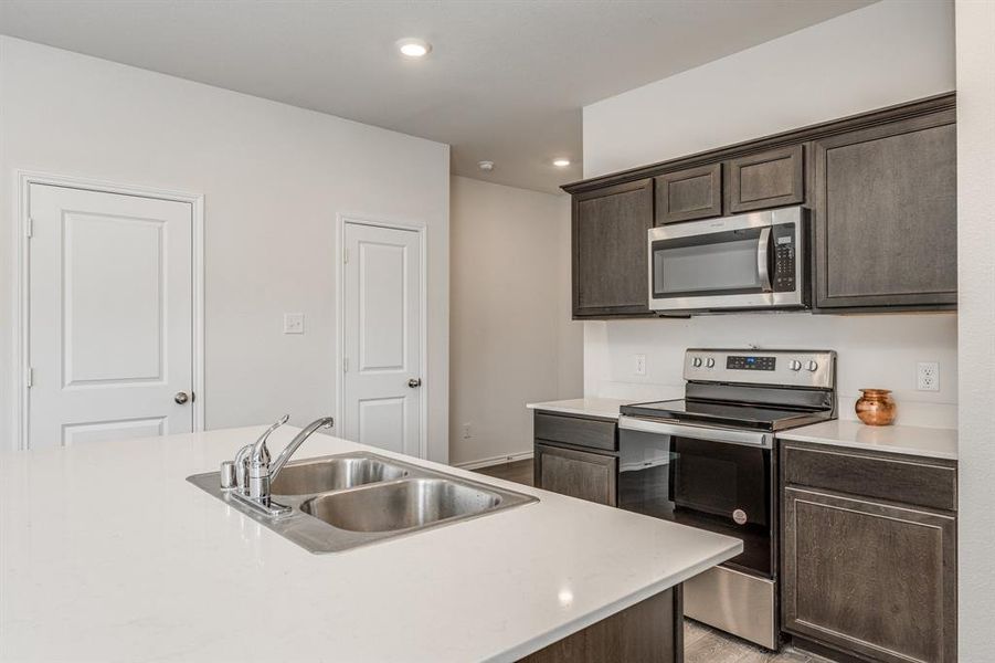 Kitchen featuring dark brown cabinets, appliances with stainless steel finishes, light hardwood / wood-style flooring, and sink