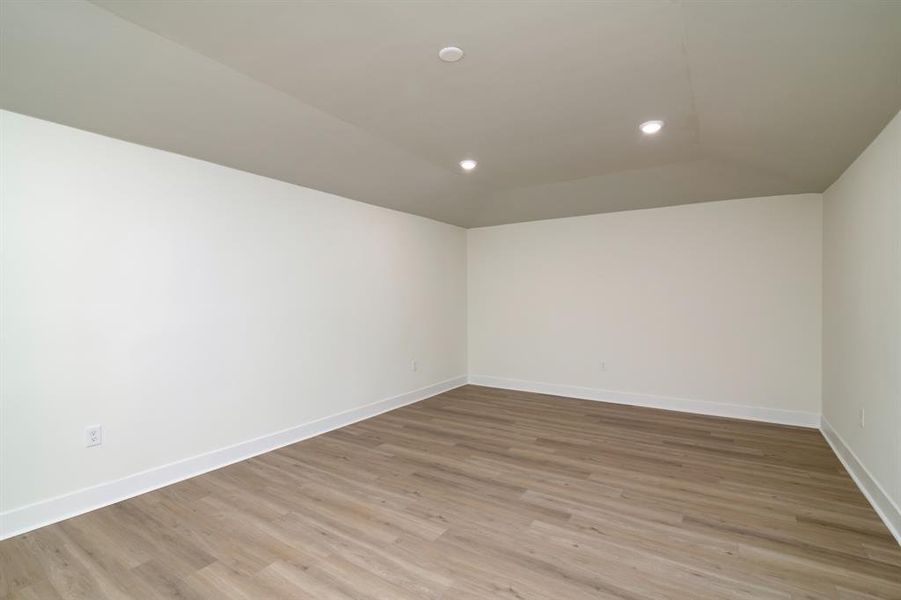 Empty room with hardwood / wood-style flooring and lofted ceiling