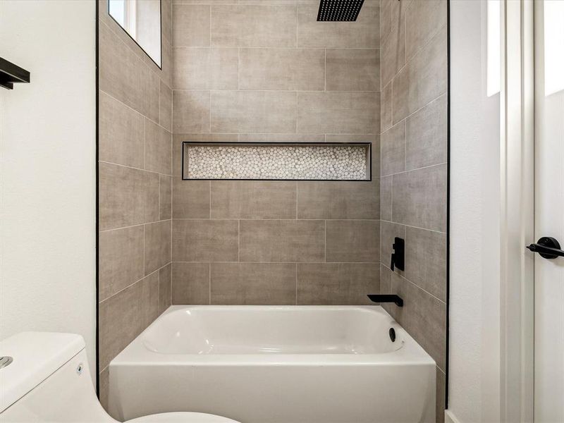 Bathroom with tiled shower / bath and toilet