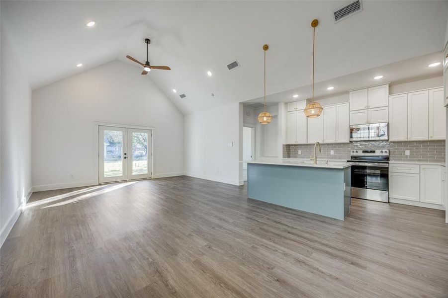 Kitchen featuring white cabinetry, pendant lighting, stainless steel appliances, and light wood-type flooring