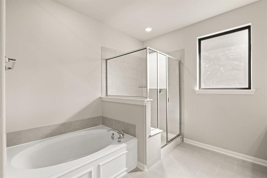 This additional view of your primary bathroom features tile flooring, fresh paint, walk-in shower, a separate garden tub, and a large walk-in closet.