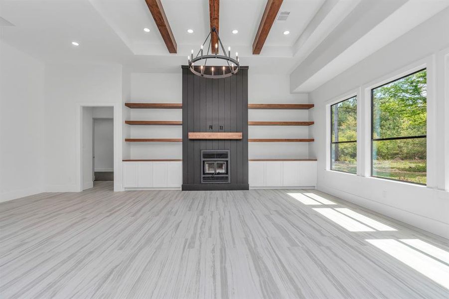 Another look at the contemporary fireplace with a dark accent wall, floating wooden shelves, and large windows providing ample natural light.