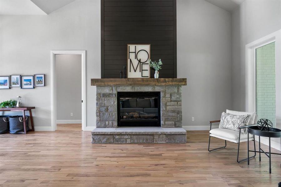 Living room with high vaulted ceiling, a fireplace, and hardwood / wood-style floors