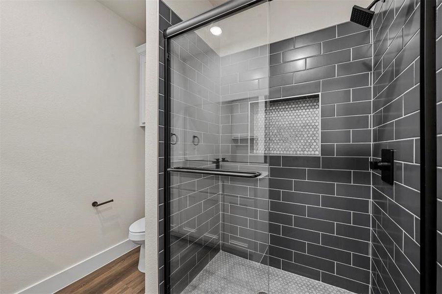 Bathroom with a shower with door, hardwood / wood-style floors, and toilet