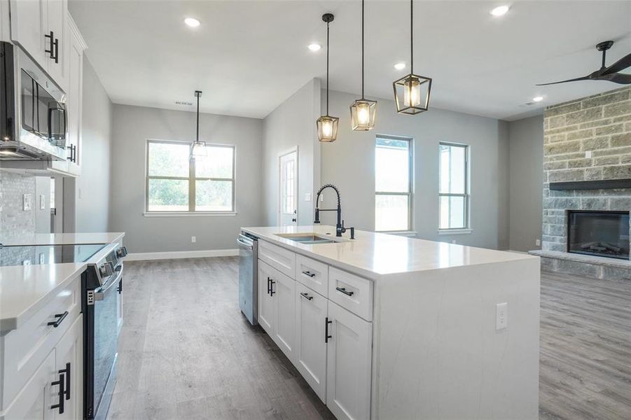 Kitchen with sink, light wood-type flooring, stainless steel appliances, and a center island with sink