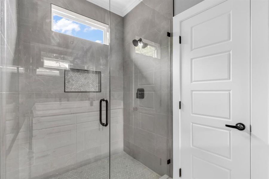 Bathroom featuring ornamental molding and a shower with door